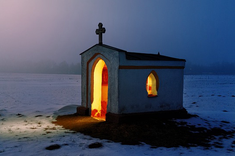 A picture of a lighted church in the snow