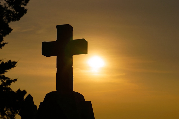 A picture of a cross in the setting sun