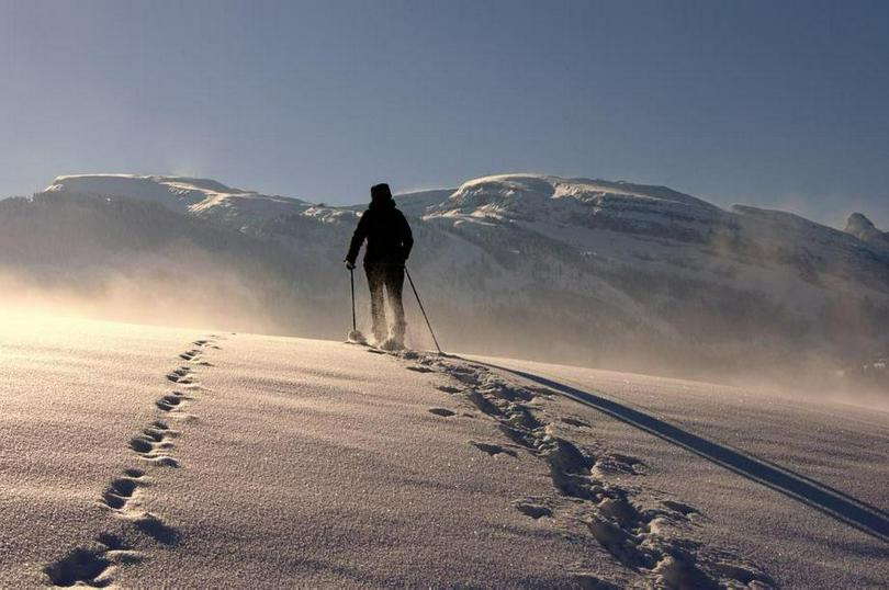 A picture of a man walking in the snow and leaving a trail of footprints