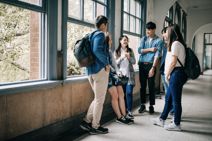 A group of young people are discussing by the windows.