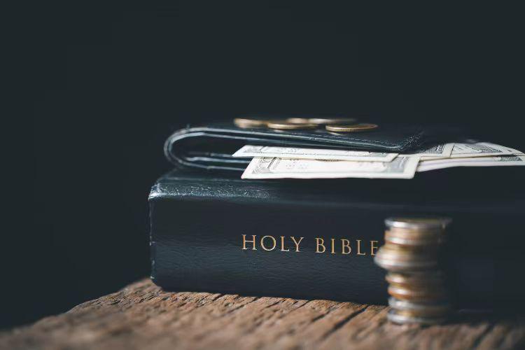 A picture of coins and money on and beside a Holy Bible