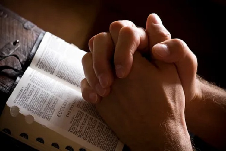 A pair of praying hands on the Bible