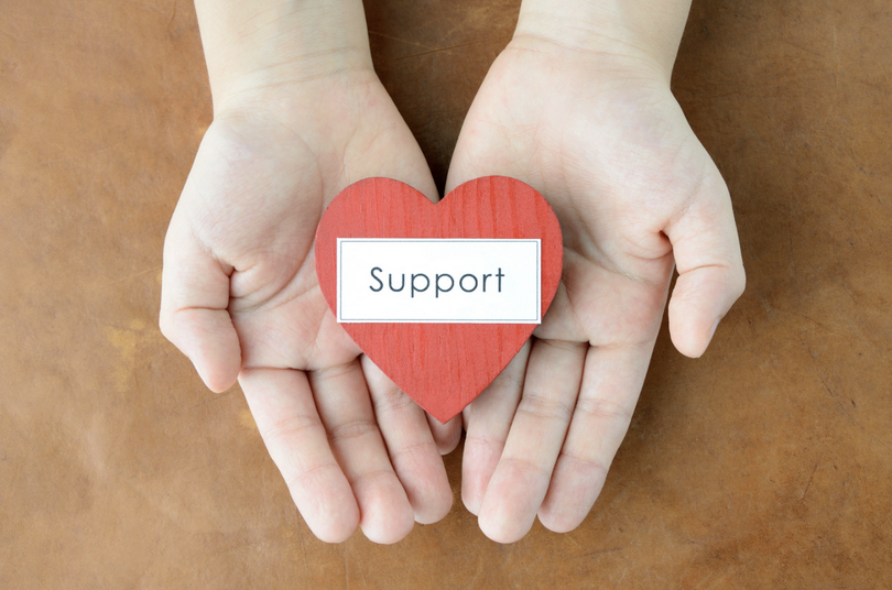 A heart-shaped wooden plate labeled as 'support' is on the hands.