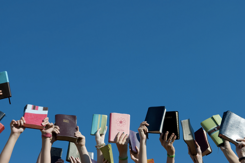 A picture of a group of young people raising up bibles