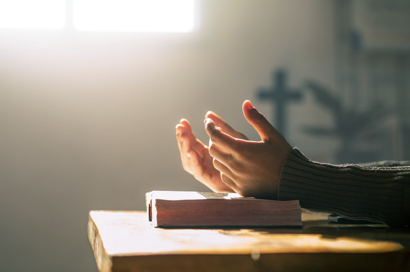 A picture of praying hands on the Bible