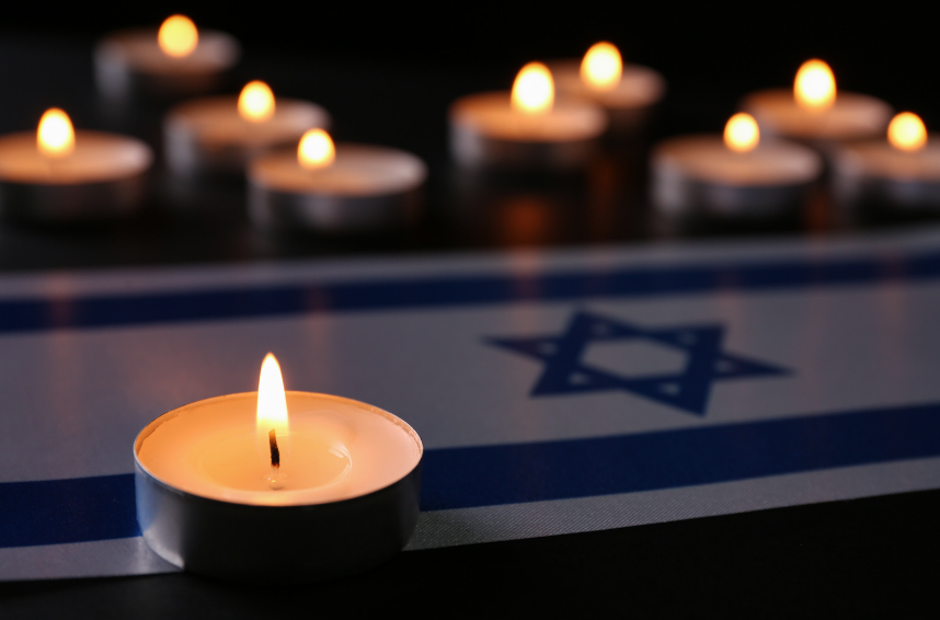 A picture of burning candles and an Israel flag on the table