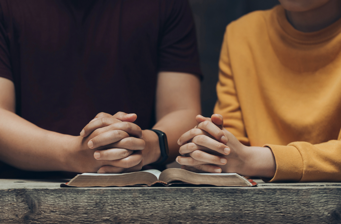 A picture of a couple’s hands praying over the Bible