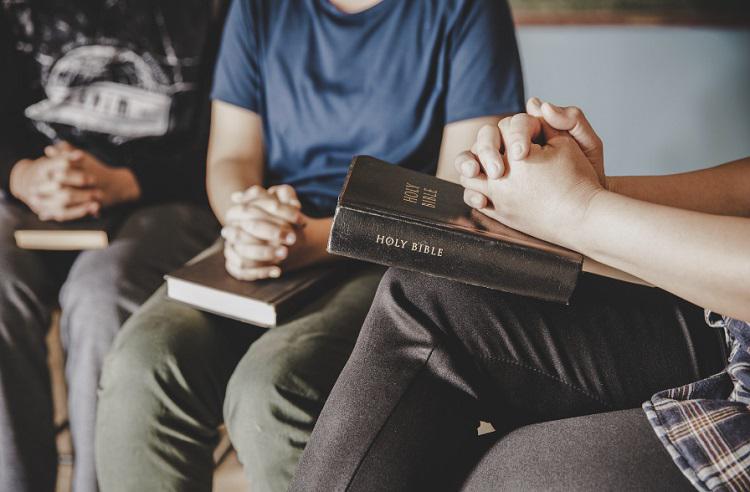 A picture of three men praying with bibles