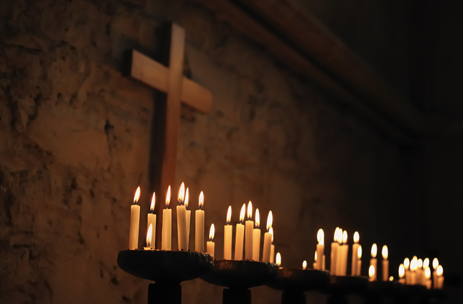 A picture of prayer candles with a wooden cross