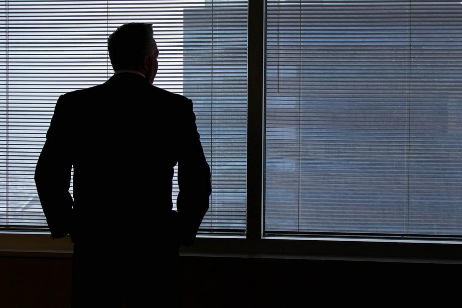 A man looks outside the window in his office. 