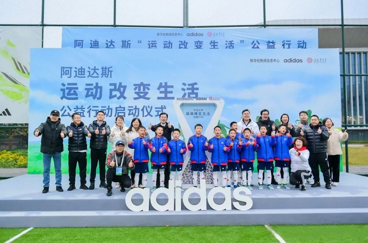 Students and staff took a group picture during a launching ceremony of the "Sport Changes Life" Public Welfare Action jointly launched by the Amity Foundation, Adidas, and the Xinhua News Agency, at the Adidas Football Fields in Shanghai, on December 11, 2023.