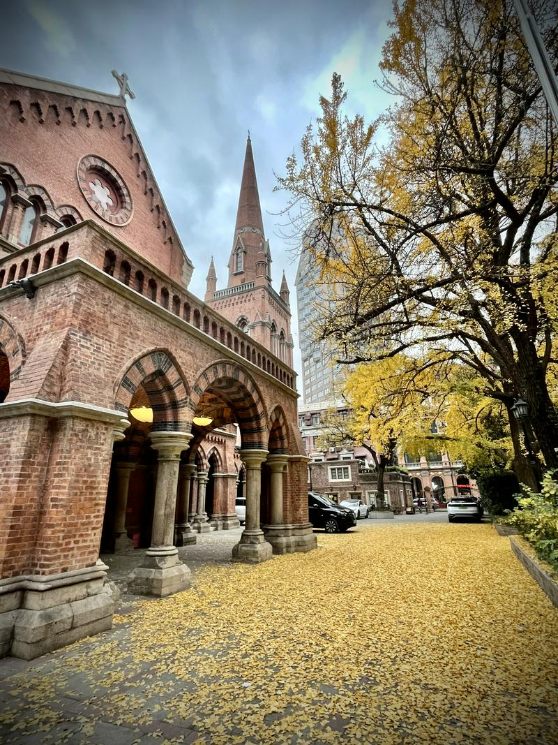 A picture of the exterior of the Holy Trinity Cathedral in Shanghai from the side, with the golden leaves spread over the ground