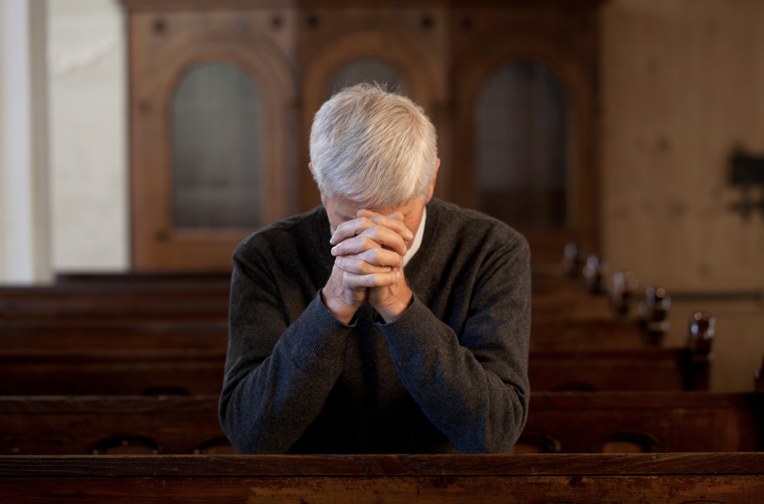 A picture of a praying senior man in a church
