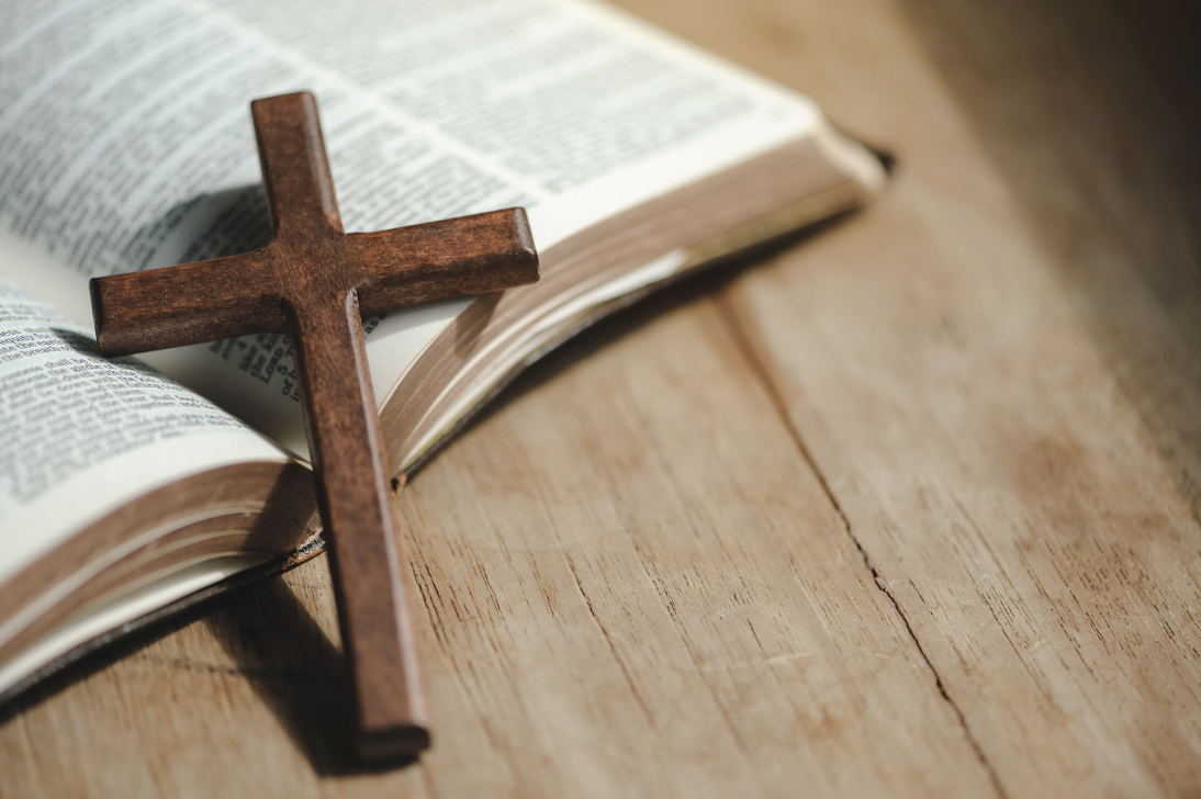 A wooden cross lays on an open Bible.