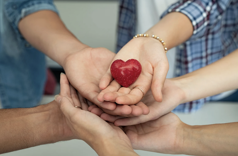 A picture of hands stacked together with a heart on top