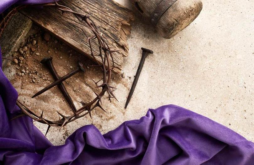 A picture of a cross with three nails and a crown of thorns on the ground