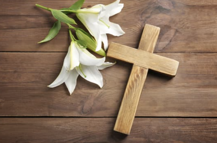 A picture of a wooden cross with lilies