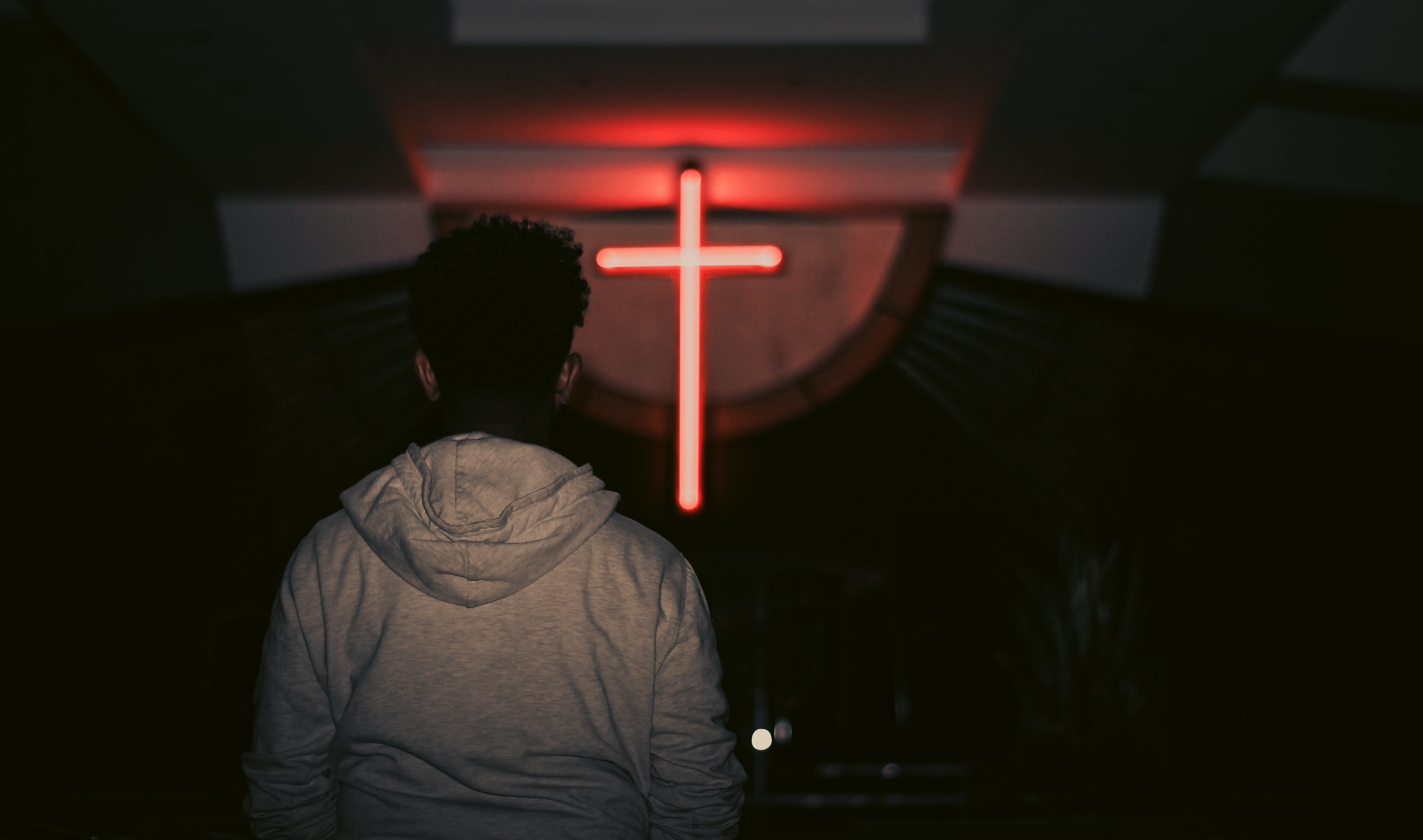 A man faces a cross at a church. 
