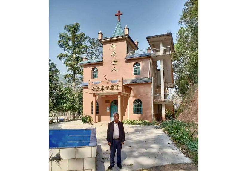 A picture of Elder Bai Rongchun with the Mohan Church in Mohan Township, Nanga Village, Mengla County, Xishuangbanna Dai Autonomous Prefecture, Yunnan Province