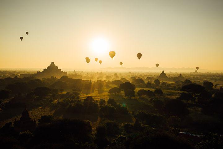 A picture of hot air balloons floating in the sky at sunset