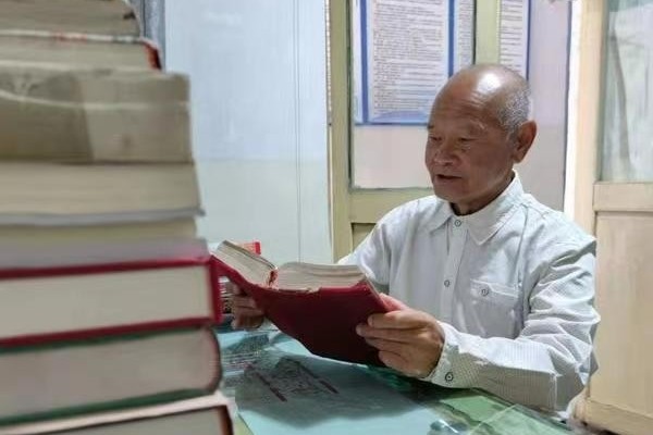 A picture of Elder He Jiming reading the Bible