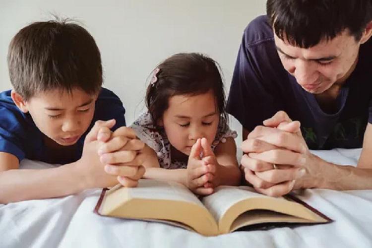 A picture of a father praying with two children