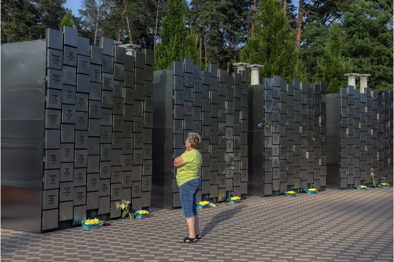 A woman looks at the memorial wall with the names of residents who were killed at the time of Russia's occupation, on July 2, 2023 in Bucha, Ukraine. The Kyiv suburb was turned into a battlefield in the first month of Russia's invasion of Ukraine, as Moscow's troops attempted to seize the capital.