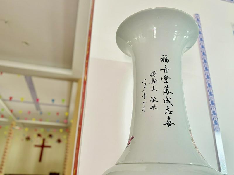 A detailed view of the neck of a large ceramic bottle displayed at Jingdezhen Church, whose characters on it offer congratulations on the church’s completion.