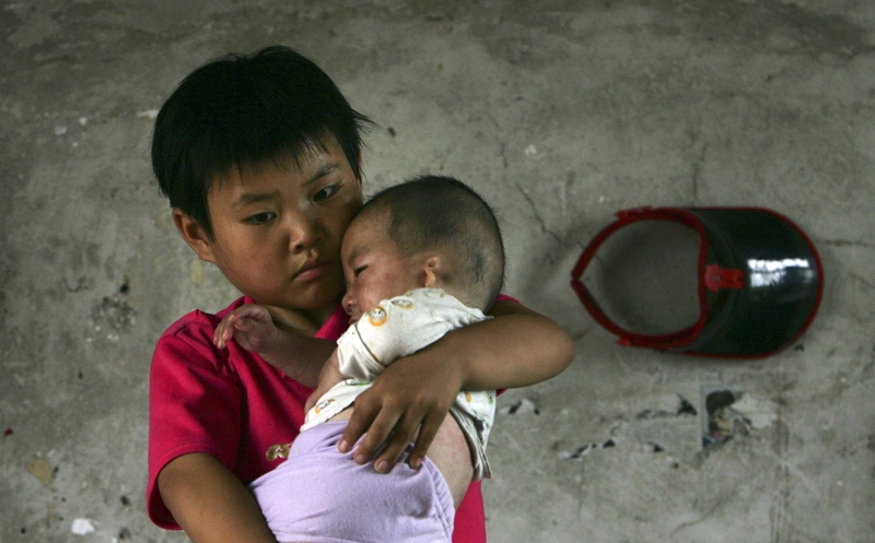 Ten-year-old Wang Huaixue holds a baby, both of them adopted at Wang Jiayu Orphanage of Sanshilipu Village on July 9, 2006 in Yingshang County of Anhui Province, China. Wang Jiayu, a 66-year-old farmer from Yingshang County in central Anhui Province, set up a special school seven years ago that specializes in caring for children adopted by him. There are currently 214 orphaned, abandoned and physically or mentally handicapped children there. 