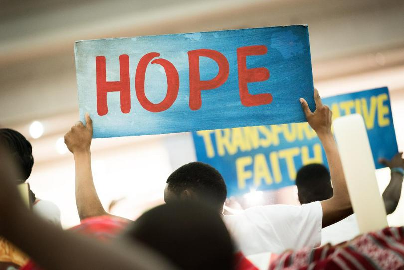 A man holds a sign of "HOPE" in a crowd.