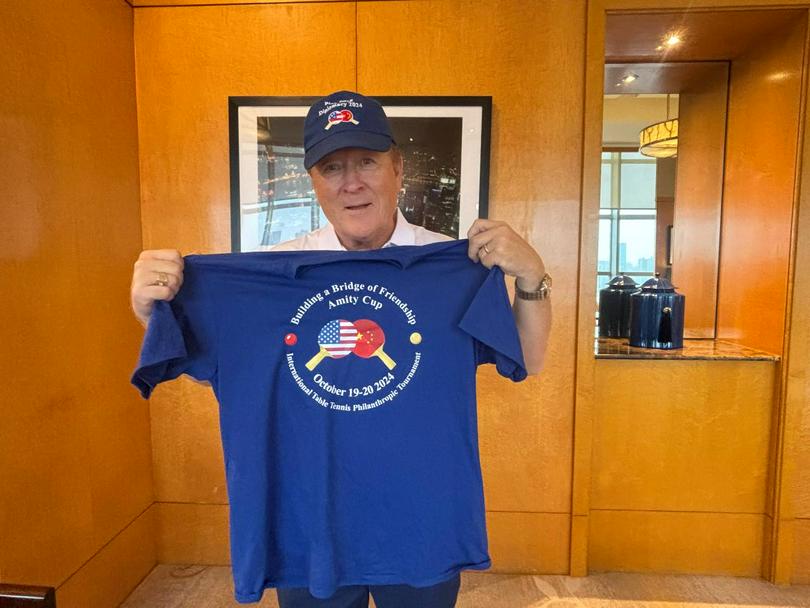 Dr. Gene Wood donned a souvenir hat and held a shirt from the First "Amity Cup" International Table Tennis Philanthropic Tournament.