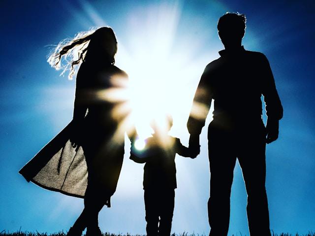 A man and woman are holding hands with a kid.