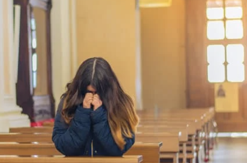 A woman prays in a church.