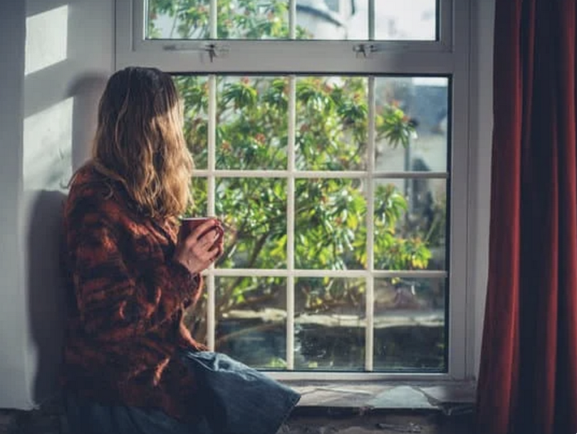 A woman looks outside from the window.