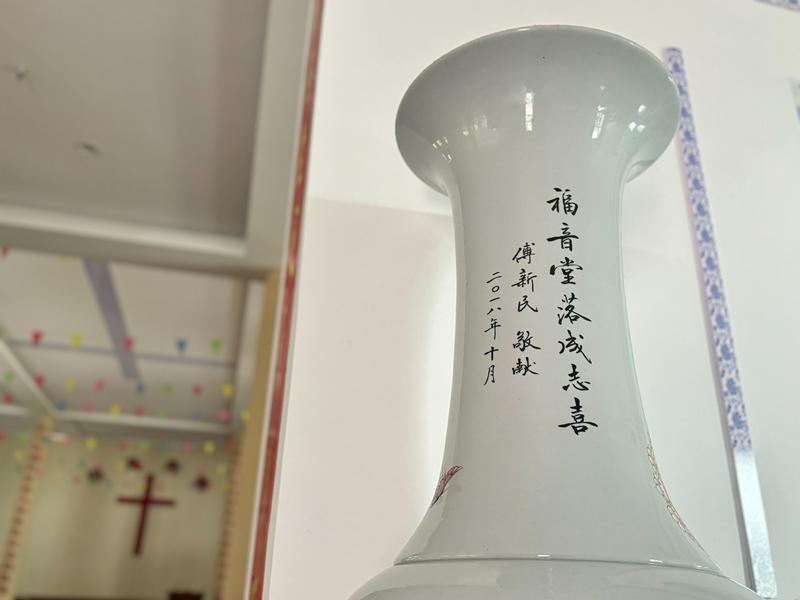 A detailed view of the neck of a large ceramic bottle displayed at Jingdezhen Church, whose characters on it offer congratulations on the church’s completion