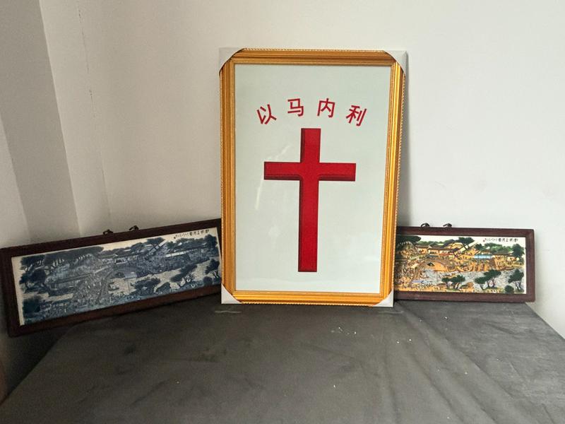 A porcelain cross stands beside both black-and-white and color versions of the famous Along the River During the Qingming Festival painting at Jingdezhen Church, in Jingdezhen City, Jiangxi Province.