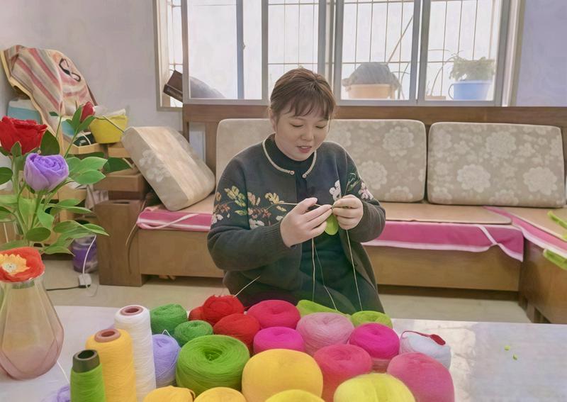 A picture shows Tujia Christian Dong Xiaohong crafting floral works.