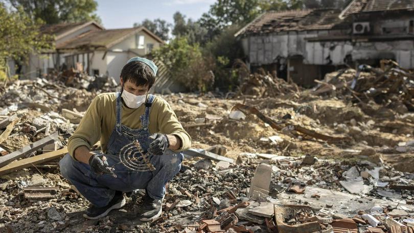 A man whose father was murdered by Hamas terrorists on Oct. 7. searched the rubble for family mementos and rescues the family menorah in Kibbutz Be’eri, Nov. 30, 2023. 