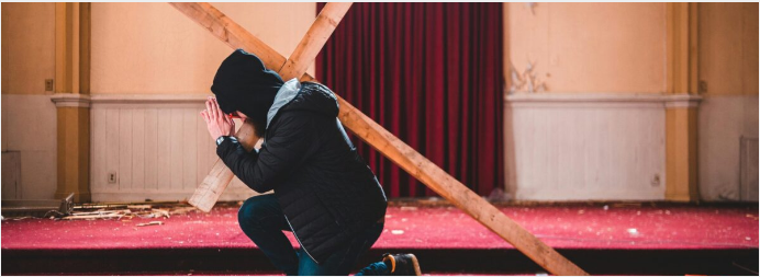 A woman carries a cross.