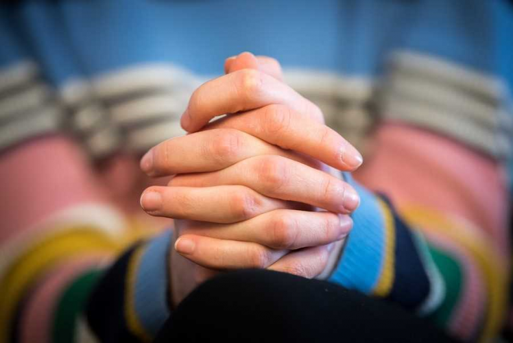 A picture shows a girl claspes her hands in prayer.