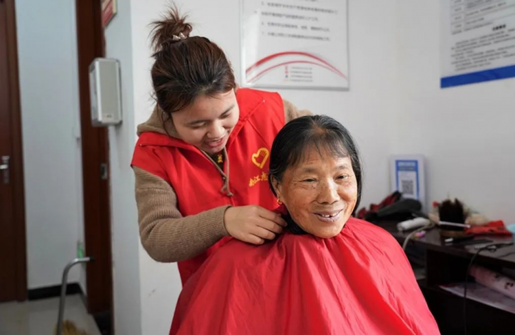 A volunteer cut hair for a senior at the Amity Foundation's "Care for Seniors Initiative" in Jiangxi Province on an unknown day.