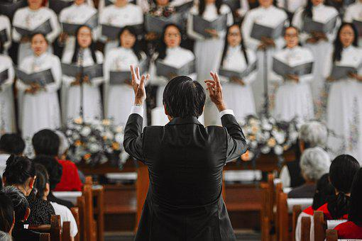 A picture of choir members presenting a hymn guided by a conductor