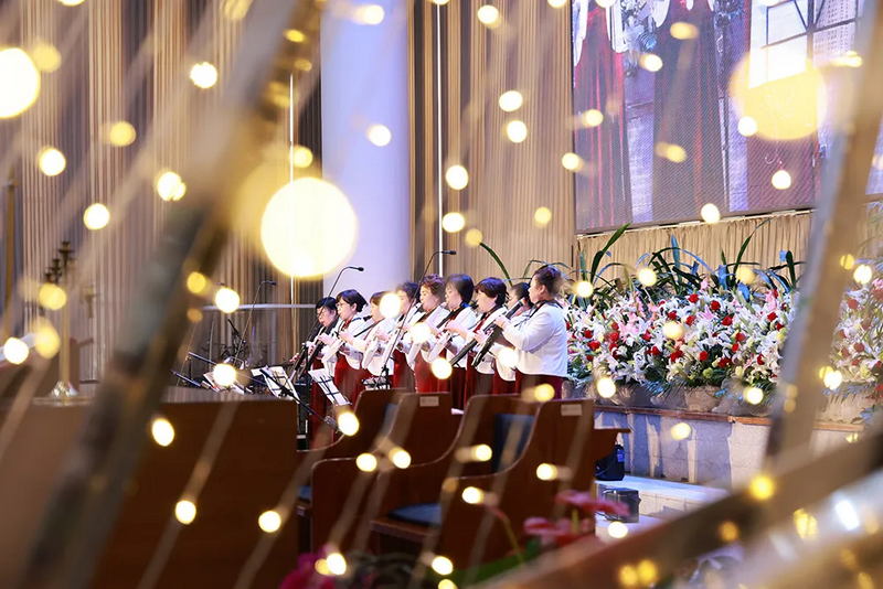 A photo captured Christian women playing instruments in celebration of Christmas at Haidian Church in Beijing on December 25, 2024, as seen through the light strips.