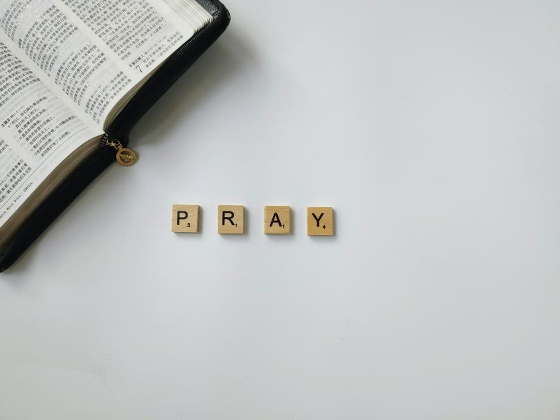 “PRAY” beside an open Bible