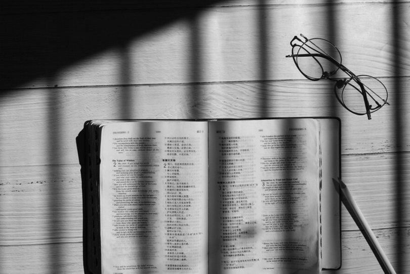 An open Chinese Bible with a pair of glasses beside