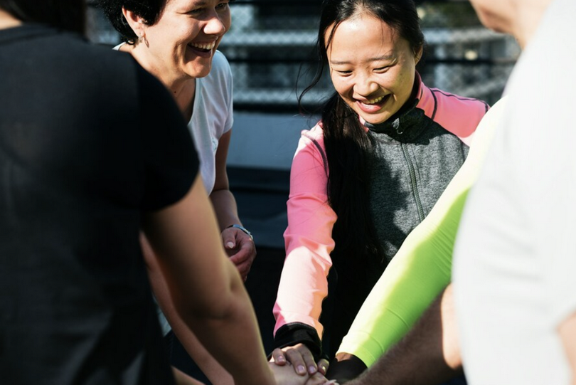 A group of people piled up their hands on an unknown day.