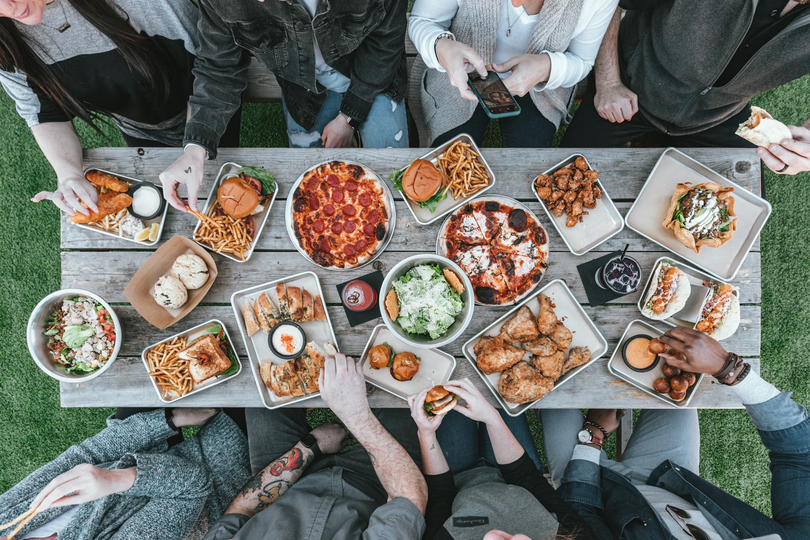 A group of people sit around a table with food.