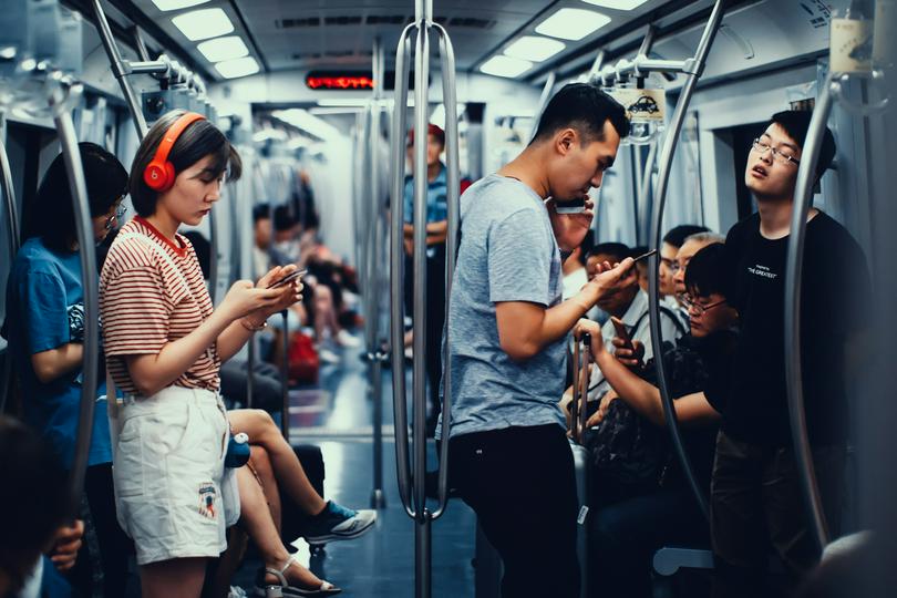 Young people using phones on the subway