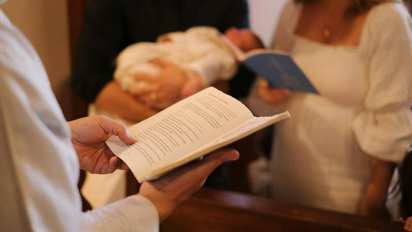 A person holds a pamphlet in front of a couple with their baby on an unknown day.