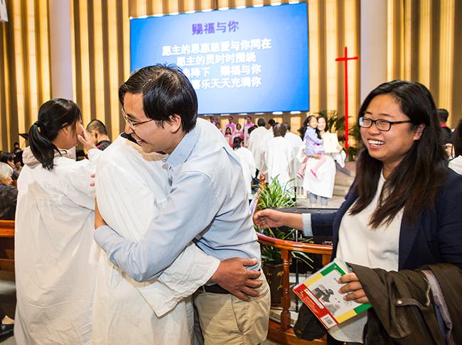 Members hug each other to express their joy after the baptism